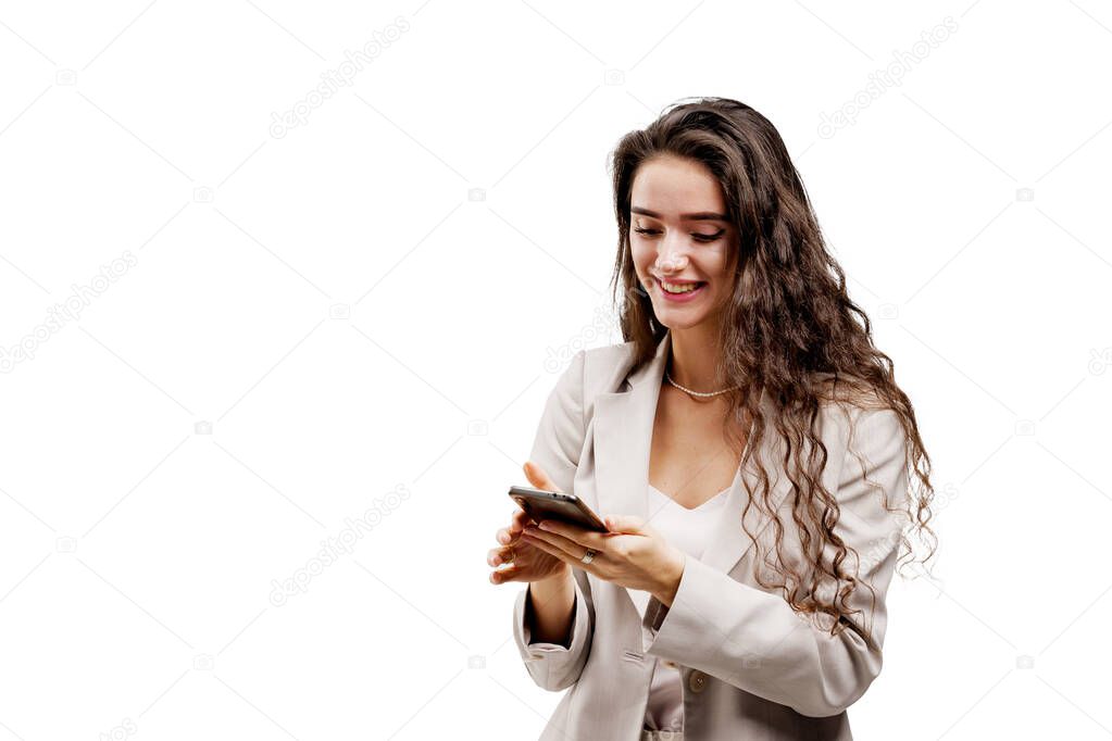 Girl is serfing on the internet using smartphone. Manager works on-line by phone. Attractive girl with curly hair holds phone and answers on messages in social networks isolated on white background