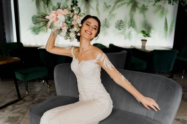 Gelinlik ve duvak giyen gelin kafedeki moda sandalyesinde oturuyor. Düğün ajansı ve gelinlik salonu için sosyal ağların adresi