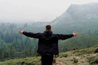 Özgürlüğü hissetmek. Turist ellerini yana kaldırdı. Dağın zirvesine tırmanıyor ve yürüyoruz.