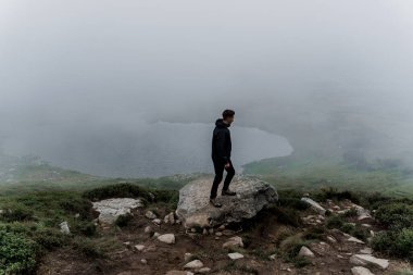Erkek turist dağın zirvesine doğru yürüyor ve seyahat ediyor. Dağın tepesine doğru yürüyüp tırmanıyor. Ukrayna 'da turizm.