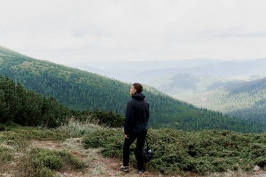 Dağın tepesine doğru yürüyüp tırmanıyor. Erkekler seyahat ediyor ve dağın dibinde dikiliyor ve zirveyi izliyor..