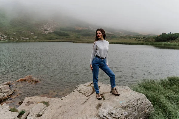 Lake at the peak of the mountain. Foggy lake. Girl is posing on the rocks.