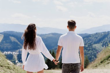 Çift sarılıyor ve dağları seyrediyor. Yeşil Tepeler 'deki mutlu kadın ve erkeklerin yaşam tarzı. Seyahat acentesine yönlendir. Turizm