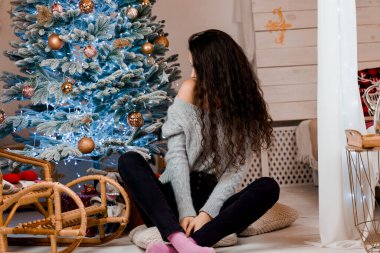 Noel ağacının yanındaki kız gülümsüyor ve poz veriyor. Yeni yıldan önce sezonluk reklamlar. Evde Noel 'i kutluyoruz.