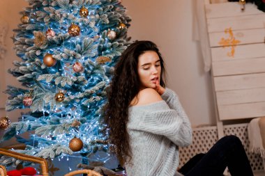 Noel ağacının yanındaki kız gülümsüyor ve poz veriyor. Yeni yıldan önce sezonluk reklamlar. Evde Noel 'i kutluyoruz.