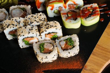 Sushi, siyah arka plana yakın plan çekim yap. Geleneksel Japon deniz ürünleri. Lezzetli rulo. Yemek dağıtım servisine yönlendir.