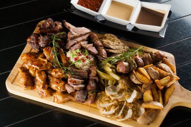 Domuz kebabı. Siyah tabakta ızgara lezzetli et. Patates, et ve sosis..