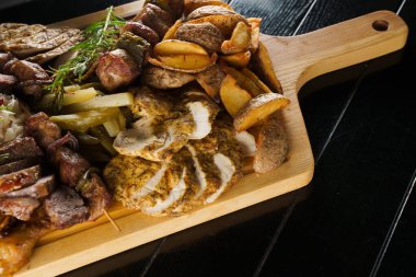 Domuz kebabı. Siyah tabakta ızgara lezzetli et. Patates, et ve sosis..