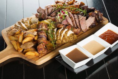 Domuz kebabı. Siyah tabakta ızgara lezzetli et. Patates, et ve sosis..