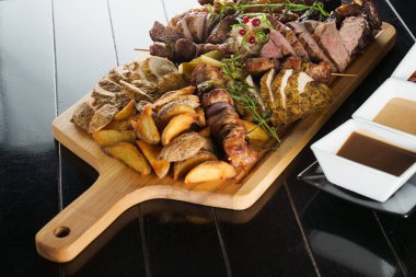 Domuz kebabı. Siyah tabakta ızgara lezzetli et. Patates, et ve sosis..