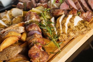 Domuz kebabı. Siyah tabakta ızgara lezzetli et. Patates, et ve sosis..