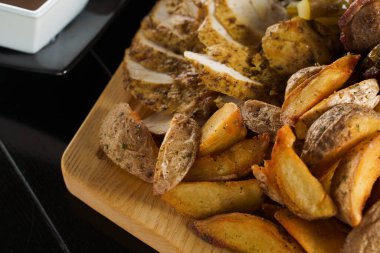 Domuz kebabı. Siyah tabakta ızgara lezzetli et. Patates, et ve sosis..