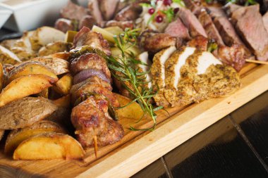 Domuz kebabı. Siyah tabakta ızgara lezzetli et. Patates, et ve sosis..