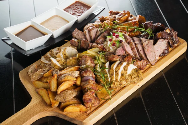 Domuz kebabı. Siyah tabakta ızgara lezzetli et. Patates, et ve sosis..