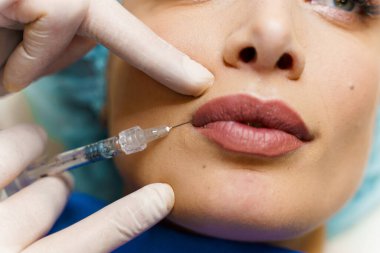 Çekici bir kız için dudak büyütme iğneleri. Estetik cerrah tıbbi klinikte dudağına iğne yapar. Kozmetik yenileme yüz tedavisi. Reklam için boş alan