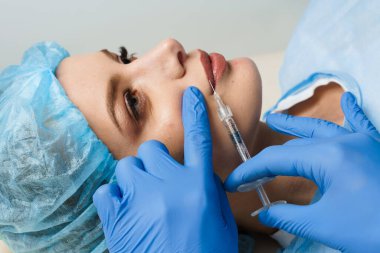 Beyaz arka planda çekici bir kız için dudak büyütme iğneleri. Estetik cerrah tıbbi klinikte dudağına iğne yapar. Kozmetik yenileme yüz tedavisi. Reklam için boş alan