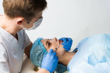 Beyaz arka planda çekici bir kız için dudak büyütme iğneleri. Estetik cerrah tıbbi klinikte dudağına iğne yapar. Kozmetik yenileme yüz tedavisi. Reklam için boş alan