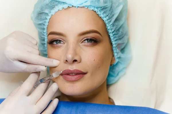 Çekici bir kız için dudak büyütme iğneleri. Estetik cerrah tıbbi klinikte dudağına iğne yapar. Kozmetik yenileme yüz tedavisi. Reklam için boş alan