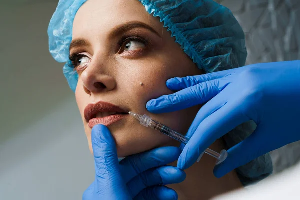 Beyaz arka planda çekici bir kız için dudak büyütme iğneleri. Estetik cerrah tıbbi klinikte dudağına iğne yapar. Kozmetik yenileme yüz tedavisi. Reklam için boş alan