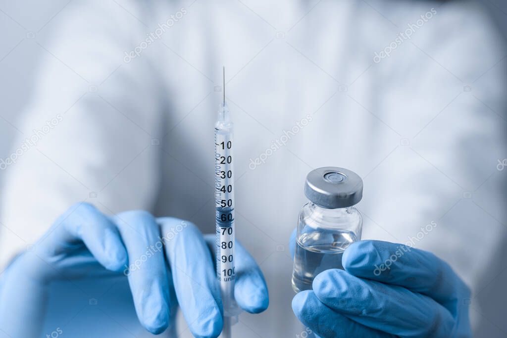 Doctor holding coronavirus vaccine. Covid-19 Vaccination. Stop quarantine. Close-up suringe and medication