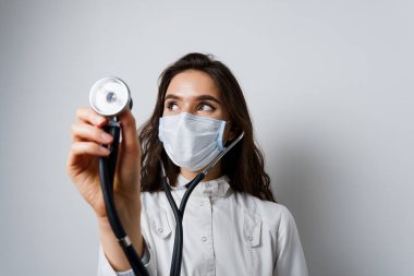 Tıbbi maskeli ve fonendoskoplu bir doktor hastaya yardımcı oluyor. Tıbbi tedavi ve tedavi. Coronavirus covid-19 için araştırma ve testler