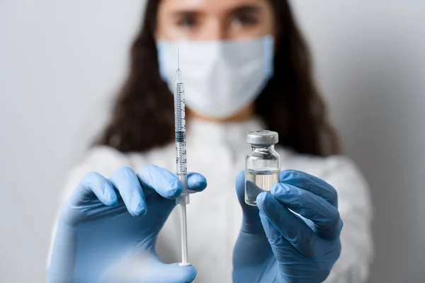 Doktor size koronavirüs aşısı yapıyor. Covid-19 Aşılama. Karantinayı durdurun. Şırıngalı ve ilaçlı tıp eldivenli çekici kız.
