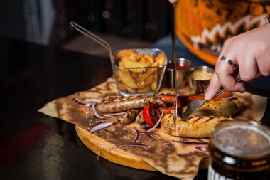 Sarı hardallı ızgara sosisli sandviç ve ahşap arka planda ketçap. Patates kızartması ve soslu sandviç..