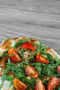 Gri ahşap arka planda Scrocchiarella İtalyan mutfağı. Geleneksel Pinsa Romana yemeği. Pizzacıdan yemek teslimatı. Etli Pinsa, roka, domates, peynir..