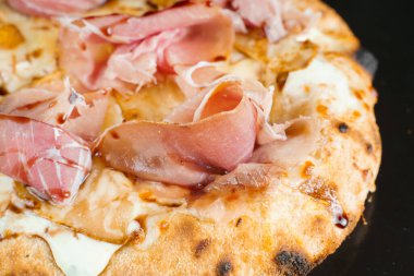 Armut, peynir ve siyah arka planda jambonlu scrocchiarella. Pinsa romana İtalyan mutfağı. Pizzacıdan yemek teslimatı. Abur cubur