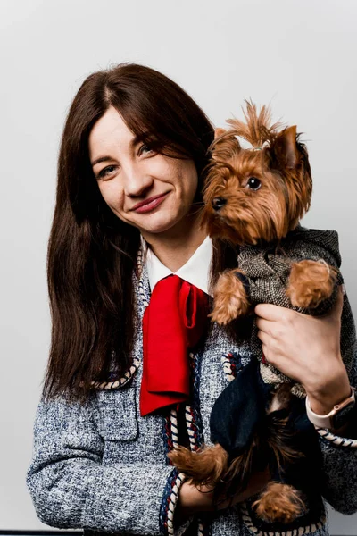 Girl holds brown dog isolated on white background. Young attractive woman with dog yorkshire terrier smiles. Close up photo. Pet care. People and pets.