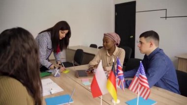 Takım çalışması. Çok ırklı bir öğrenci grubunda çalışmak. Öğretmen sınıfta birlikte yabancı diller öğreniyor. Laptopla çalışıyorum. Siyahi, yakışıklı kız öğrenci, beyazlarla birlikte çalışıyor.