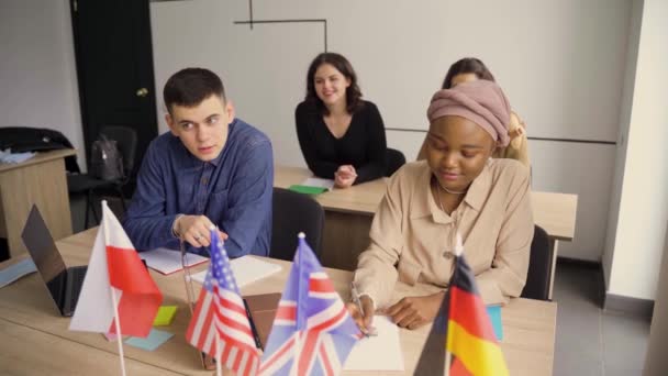 外国学校和一个女学生私自学习。老师用笔记本电脑讲解母语语法.准备与导师一起参加考试。前面的英国、英国、德国和波兰国旗. — 图库视频影像