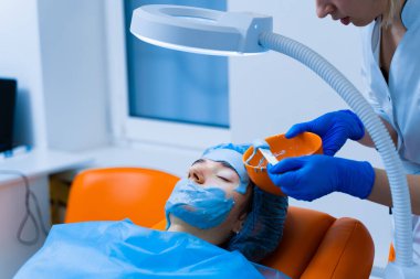 Genç bir kızın yüzü ve teni için nemlendirici maske. Yenilenme için spa prosedürü. Güzellik uzmanı maske sürüyor. Tıp kliniğinde dermatoloji