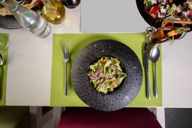 Siyah tabakta ıspanaklı, peynirli ve fesleğenli makarna. Güzel bir restoran yemeği. Tablo ayarı.