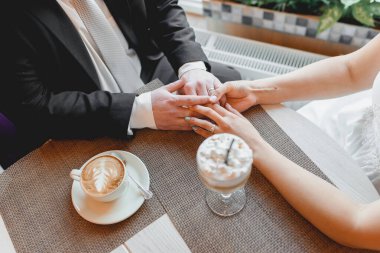 Gelin ve damat el ele tutuşuyor. Romantik bir an. Kapuçino ve marşmelovlu latte..