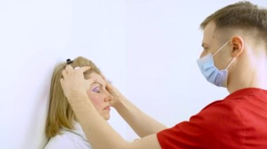 Tıbbi klinikteki yüz bölgesini değiştiren estetik ameliyattan önce yüzünde Blepharoplasti izi var. Estetik ameliyat yapan bir doktor.
