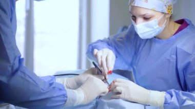 Tıbbi klinikte yüz bölgesinin değiştirilmesi için Blepharoplasty estetik ameliyatı. İki doktor kadınlar için estetik ameliyat yapıyor. Cerrah göz kapağına dikiş atar.