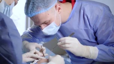 Tıbbi klinikte yüz bölgesinin değiştirilmesi için Blepharoplasty estetik ameliyatı. İki doktor kadınlar için estetik ameliyat yapıyor. Cerrah göz kapağına dikiş atar.