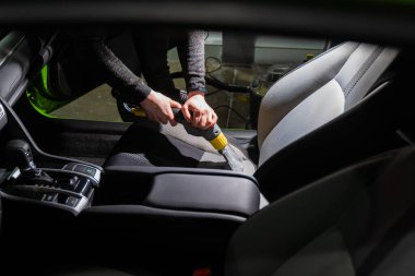 Elektrikli süpürgeyle araba yıkama salonunu temizliyorum. Buhar süpürgesinin lekeleri çıkarmak için profesyonel kullanımı.