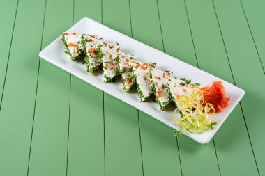 Yeşil arka planda beyaz bir tabakta yumuşak krem peynirli güzel atıştırmalıklar. Somon ve otlu süzme peynirli atıştırmalıklar..