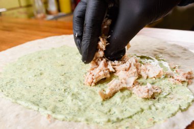 Burrito pişirme işlemi. Aşçı soslu pita 'ya et ekler. Burrito yapma süreci. Meksika yemeği.