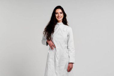 Beyaz arka planda kıvırcık saçlı, tıp kıyafetli kız cerrah. Koronavirüsün üçüncü dalgası covid-19 epidemi..