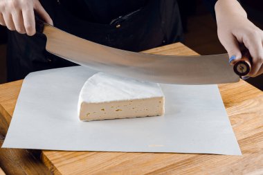 İnek sütünden krem peynir. Tahta masada peynir dilimliyorum. Organik lezzetli yemekler.