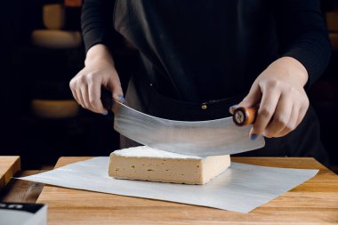 İnek sütünden krem peynir. Tahta masada peynir dilimliyorum. Organik lezzetli yemekler.