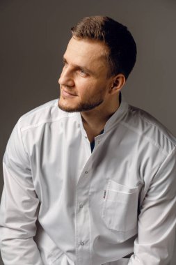 Siyah arka planda tıbbi elbise giymiş bir cerrah. Stüdyoda poz veren yakışıklı doktor