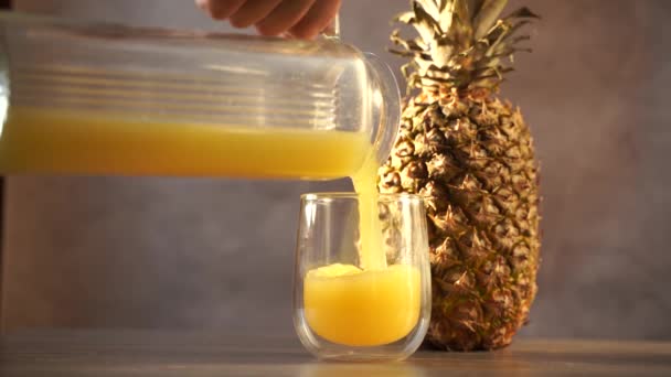 Owoce i sok ananasowy w szklanej filiżance. Wlewanie soku tropikalnego do szkła. — Wideo stockowe