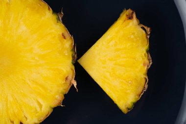 Mavi tabakta bir parça ananas, yakın plan. Sarı tropik meyve dilimi.
