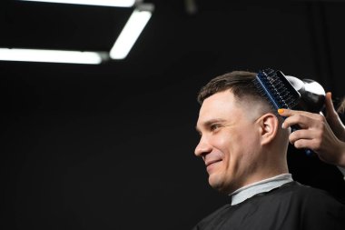 Yakışıklı bir adam için berber dükkanında saç kestikten sonra saç kurutmak. Kadın kuaför saç stili yapıyor.