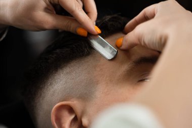 Berber dükkanında ustura kesimi erkek saçı. Çekici kadın berber yakışıklı bir adam için saç stili yapıyor.