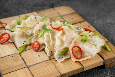 Tahta tabakta Gyoza adında Jiaozi Çin mantısı. Geleneksel Asya fast food. Et ve sebzelerle doldurulmuş hamur tabağı, daha az sıklıkla et.